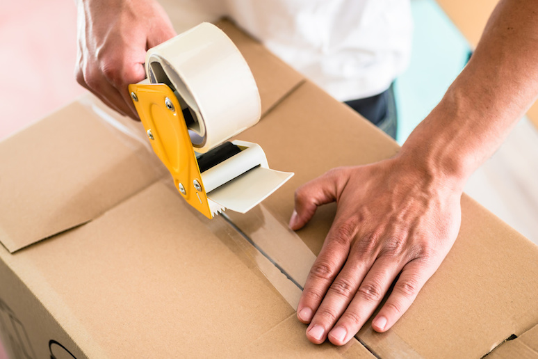 Man sealing a box with a packing tape.